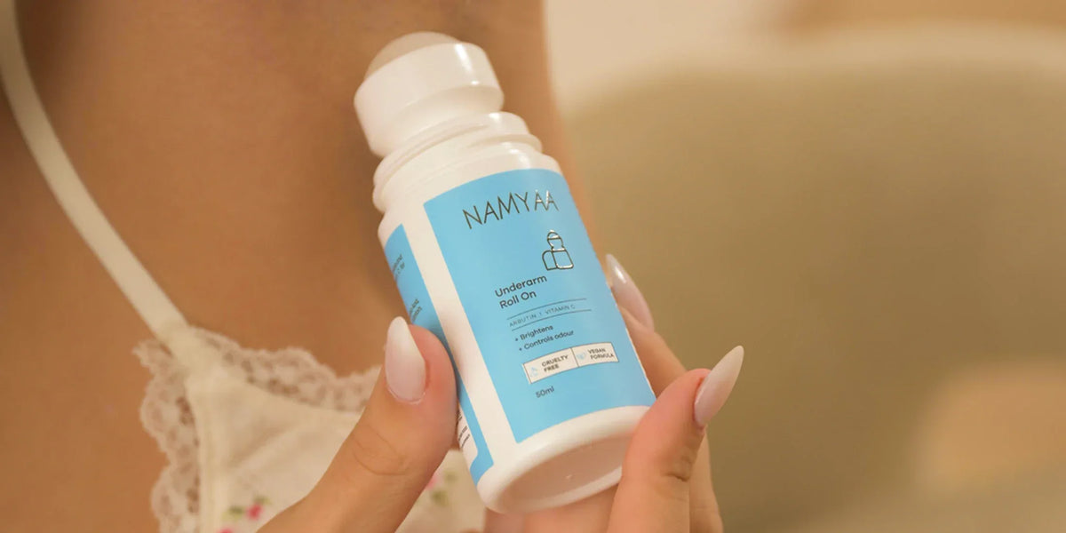Close-up of a woman holding the open Namyaa Underarm Roll-On bottle