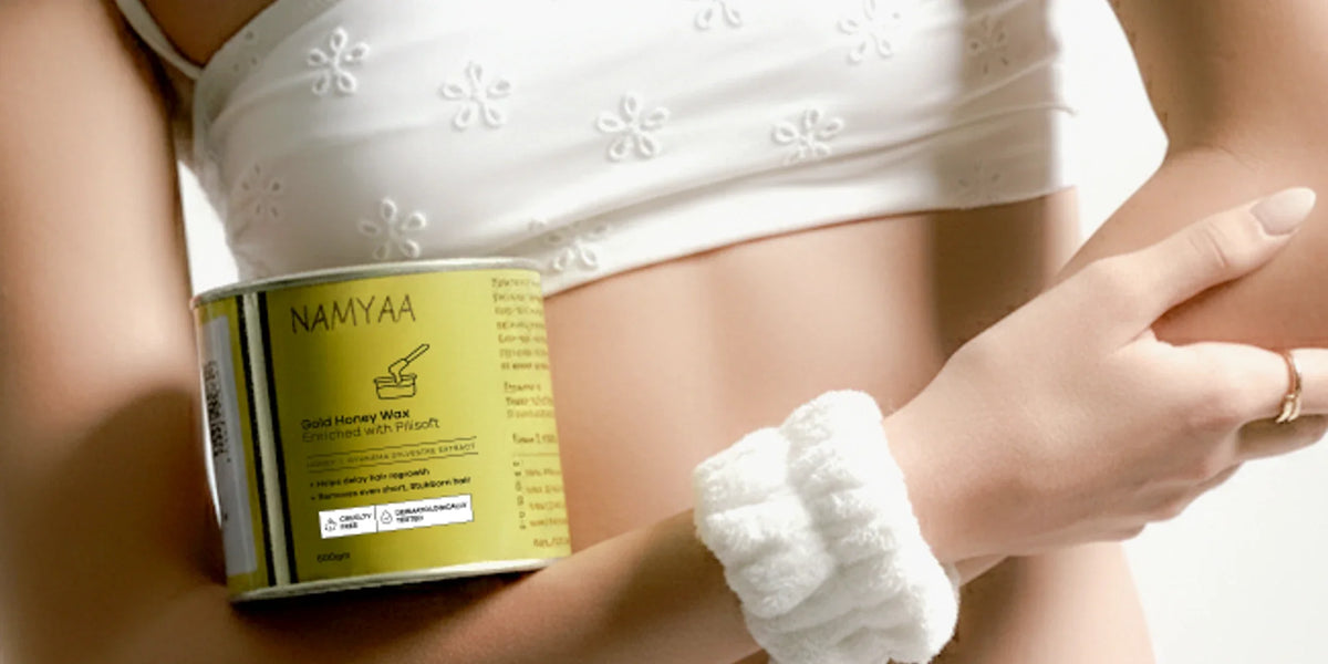 Woman holding a Namyaa Gold Honey Wax tin against her forearm with a soft scrunchie