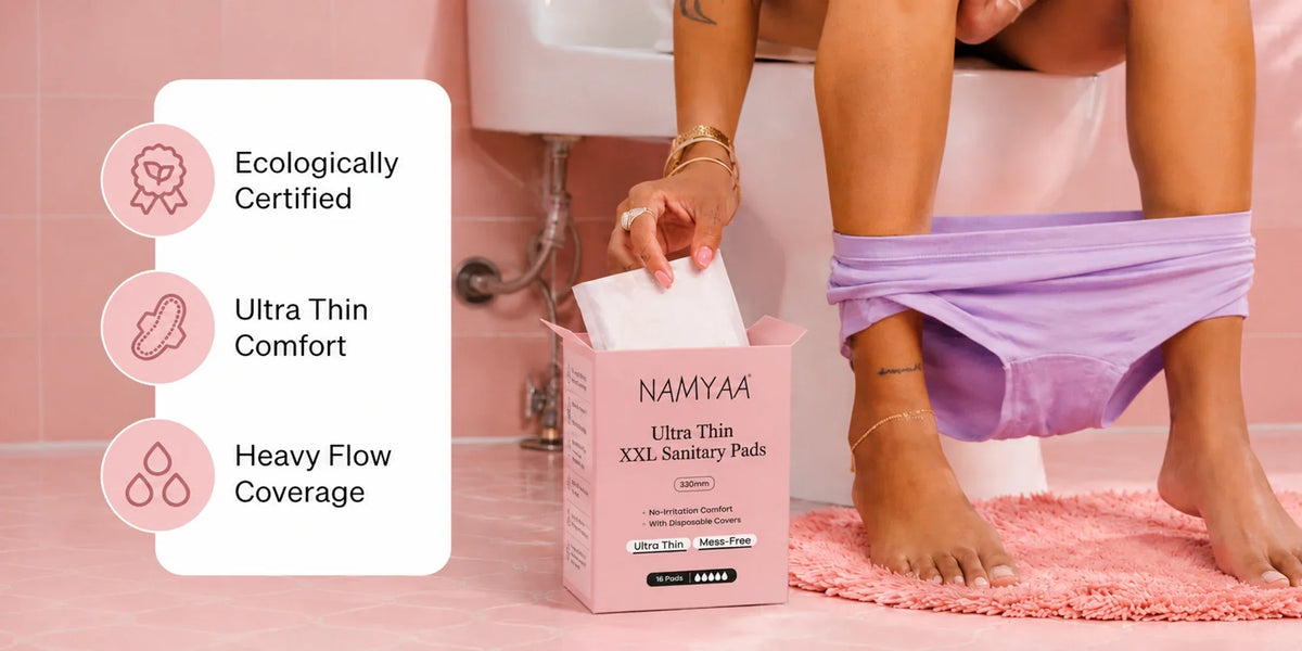Woman seated in a bathroom taking an individually wrapped sanitary pad from a Namyaa box