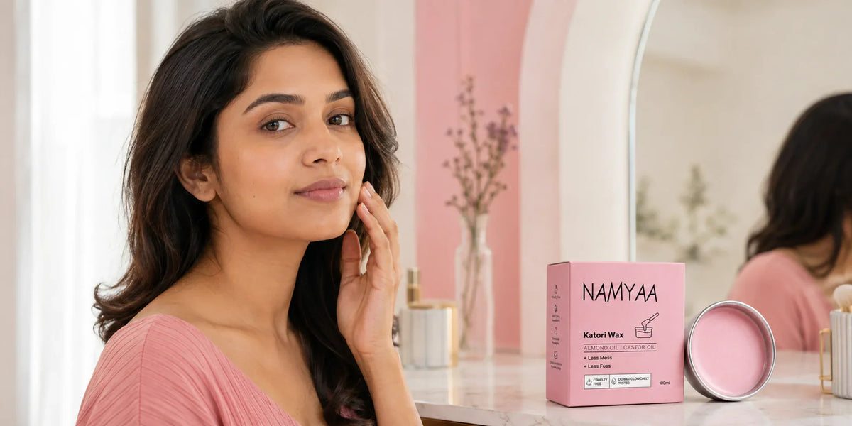 Adult Indian woman touching her cheek beside Namyaa Katori Wax on a vanity.