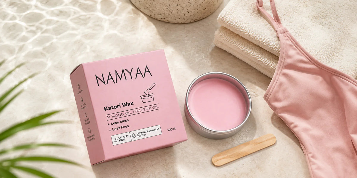 Namyaa Katori Wax in a discreet flat lay with a towel, swimsuit and wooden applicator.