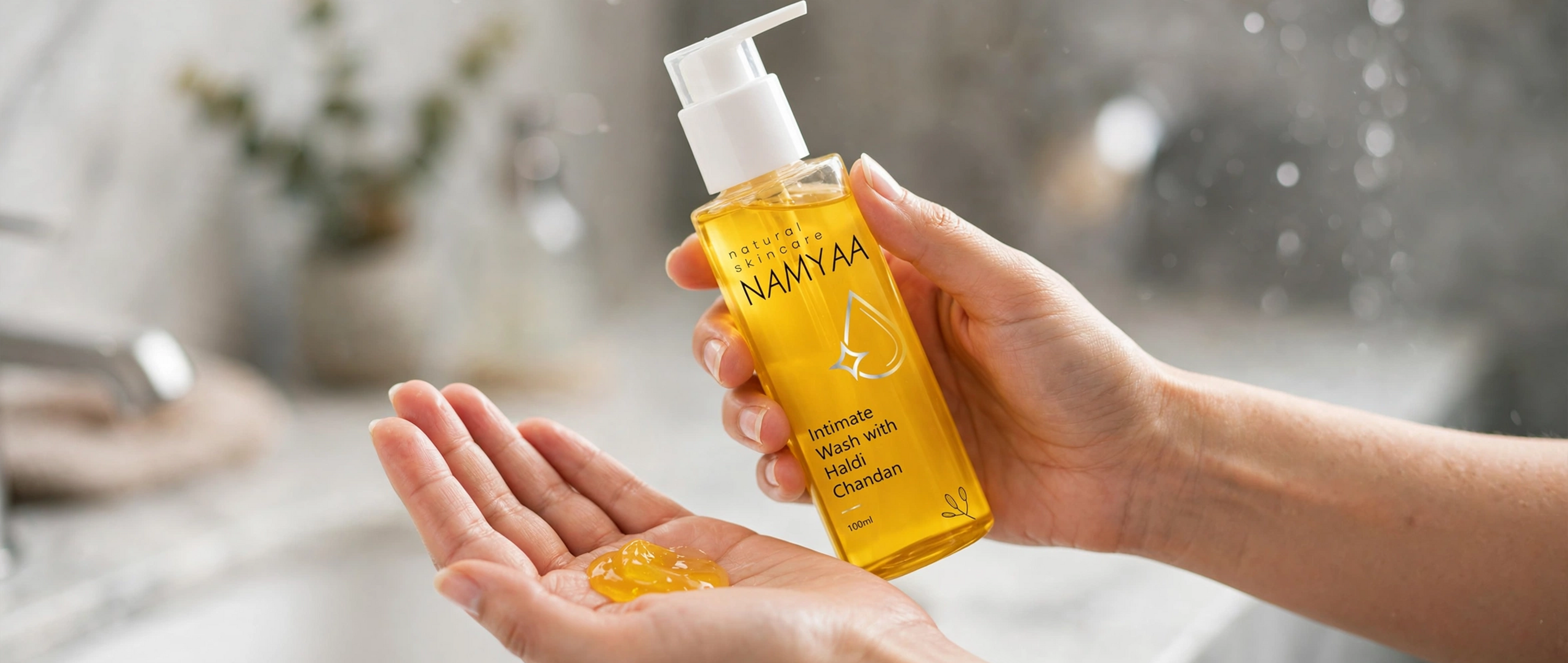 A person pouring a dollop of yellow gel onto their open hand from a clear pump bottle of Namyaa Intimate Wash with Haldi Chandan.