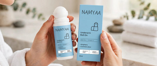 Hands holding light blue Namyaa Underarm Roll On bottle and box enriched with Arbutin and Vitamin C for brightening and odor control
