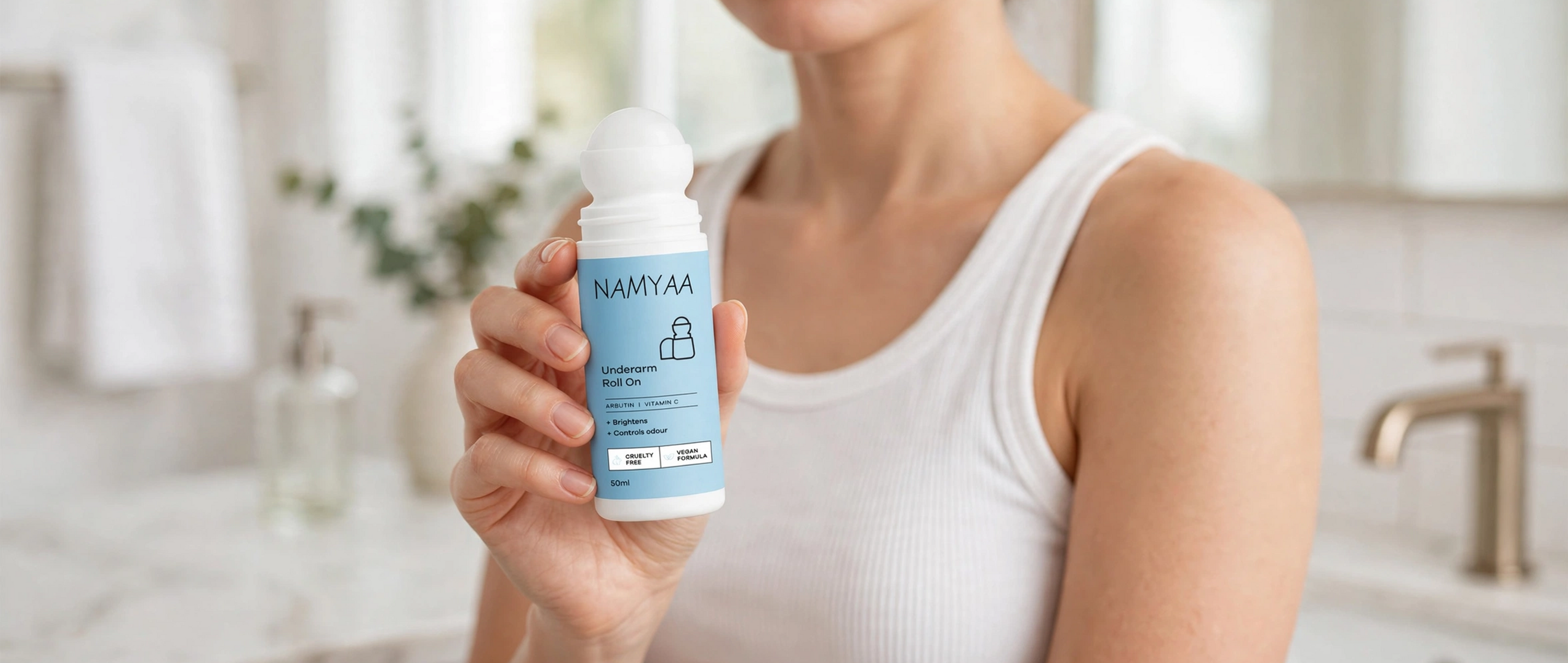 Woman holding Namyaa Underarm Roll On bottle designed to brighten skin and control body odor